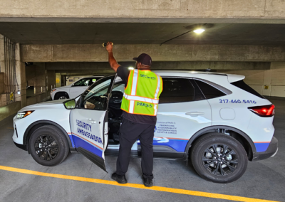 Security Ambassador at patrol car, checking for suspicious activity in the parking garage